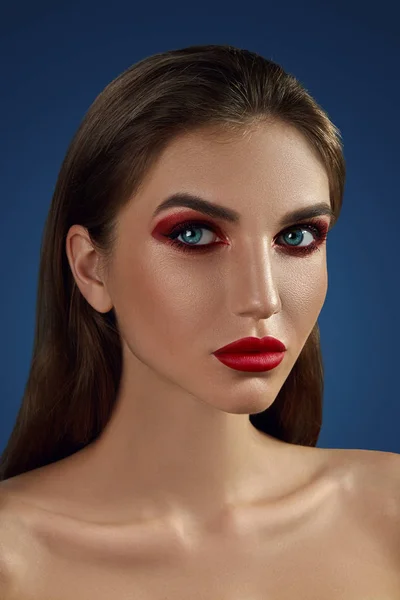 Glamour-Porträt eines schönen halbnackten Models in Nahaufnahme, das mit hellem Make-up vor blauem Hintergrund posiert. — Stockfoto