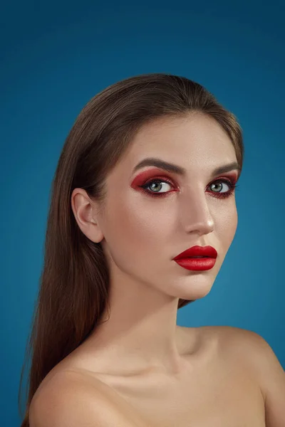 Close-up glamour portrait of a beautiful half-naked model with bright make-up posing over a blue background. — Stock Photo, Image