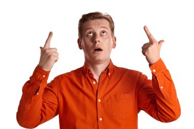 Tarz sahibi turuncu tişörtlü genç bir zencefil pesonun yakın plan portresi işaret parmaklarını kaldırdı ve beyaz stüdyo arka planında izole bir şekilde poz verirken yukarı baktı. İnsan yüz ifadeleri. Samimi duygular konsepti. Boşluğu kopyala.