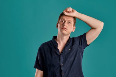 Mavi stüdyo arka planında poz verirken yorgun görünen şık bir donanma tişörtü giyen zeki bir zencefilin yakın plan portresi. İnsan yüz ifadeleri. Samimi duygular konsepti. Boşluğu kopyala.