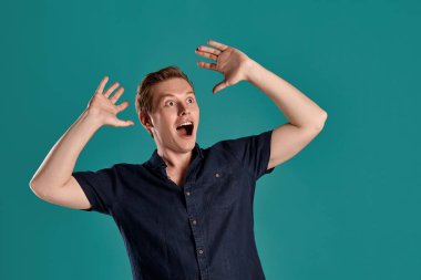 Mavi stüdyo arka planında poz verirken şık bir donanma tişörtü giymiş, korkmuş ve kremlenmiş genç bir kızıl adamın yakın plan portresi. İnsan yüz ifadeleri. Samimi duygular konsepti. Boşluğu kopyala.