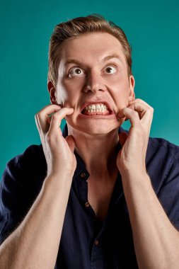 Mavi stüdyo arka planında poz verirken şık bir donanma tişörtü giymiş genç zencefilli pesonun yakın plan portresi. İnsan yüz ifadeleri. Samimi duygular konsepti. Boşluğu kopyala.