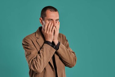 Sakallı ve bıyıklı orta yaşlı bir adam, siyah gömlek ve mavi bir arka plan aleyhine poz kahverengi ceket giyer. Samimi duygular kavramı.