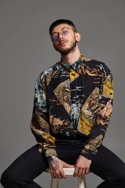 Retrato de cerca de un tipo divertido posando sentado en una silla de bar en un estudio aislado sobre fondo gris . — Foto de Stock