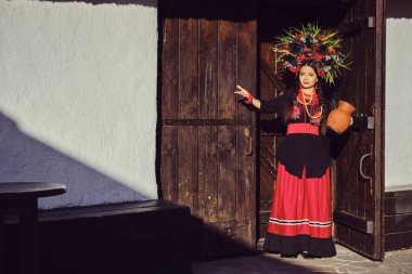 Beyaz ukraynalı otantik ulusal kostüm ve çiçek çelenk esmer kız kapıda ayakta poz.