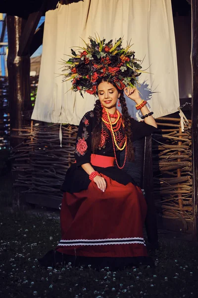 Brunetka dziewczyna w białym ukraińskim autentycznym Narodowym stroju i Wieniec kwiatów stwarza na taras. Zbliżenie. — Zdjęcie stockowe