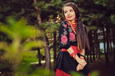 Beyaz ukrayna otantik ulusal kostüm ve çiçek çelenk esmer kız bir ahşap poz olduğunu. Close.