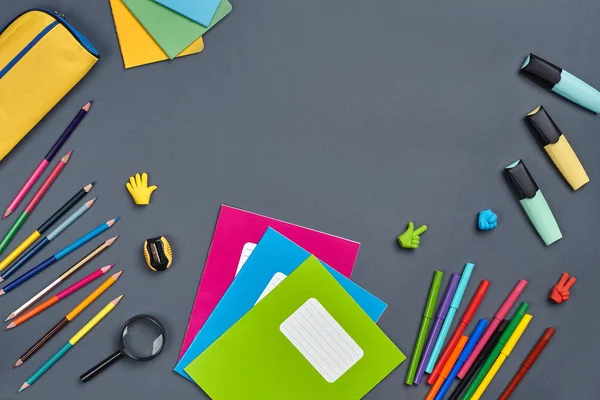 Flat lay photo of workspace desk with school accessories or office supplies on gray background.