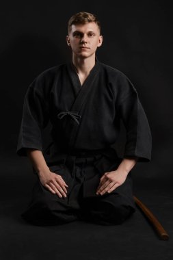 Geleneksel Japon kimonosu giymiş Kendo gurusu Shinai bambu kılıcıyla siyah bir stüdyoda dövüş sanatları eğitimi alıyor..