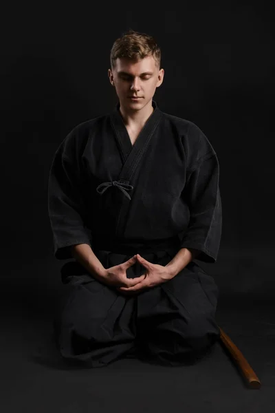 Kendo guru indossa in un tradizionale kimono giapponese sta praticando l'arte marziale con la spada di bambù shinai su uno sfondo da studio nero. — Foto Stock