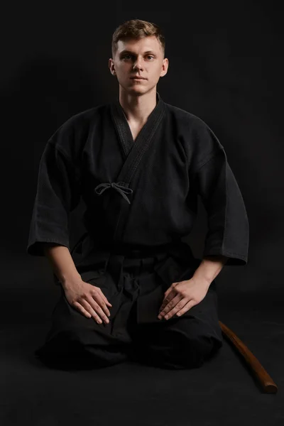 Kendo goeroe draagt in een traditionele Japanse kimono is het beoefenen van krijgskunst met de shinai bamboe zwaard tegen een zwarte studio achtergrond. — Stockfoto