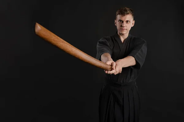 Kendo guru na sobě v tradičním japonském kimonu cvičí bojové umění s bambusovým mečem Shinai na černém pozadí studia. — Stock fotografie