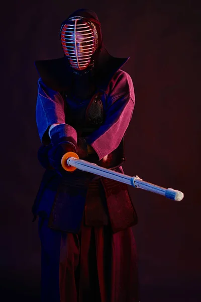 Närbild skott, Kendo fighter bär i en rustning, traditionell kimono, hjälm öva kampsport med shinai bambu svärd, svart bakgrund. — Stockfoto