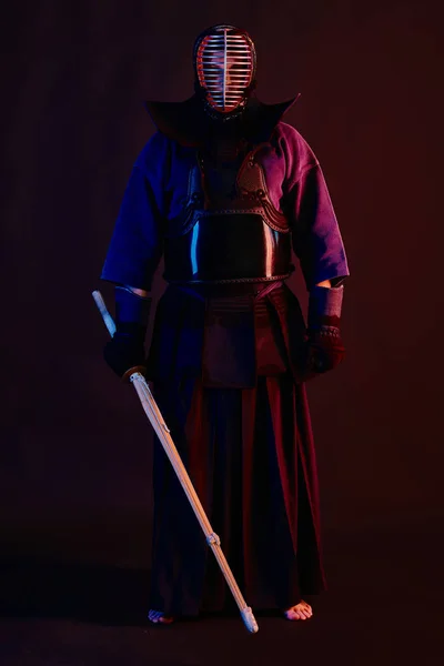 Close-up schot, Kendo vechter dragen in een harnas, traditionele kimono, helm beoefenen van krijgskunst met shinai bamboe zwaard, zwarte achtergrond. — Stockfoto