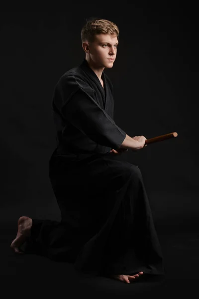 Kendo guru indossa in un tradizionale kimono giapponese sta praticando l'arte marziale con la spada di bambù shinai su uno sfondo da studio nero. — Foto Stock