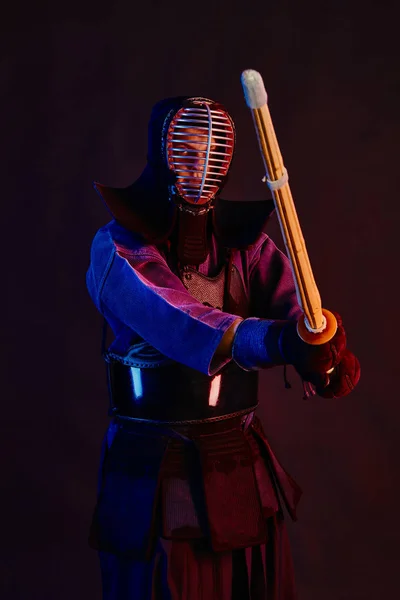 Nahaufnahme, Kendo-Kämpfer in Rüstung, traditioneller Kimono, Helm als Kampfkunst mit Shinai-Bambusschwert, schwarzer Hintergrund. — Stockfoto