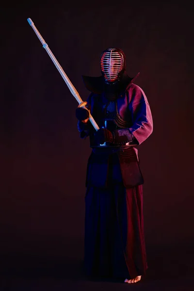 Strzał z bliska, myśliwiec Kendo w zbroi, tradycyjne kimono, kask ćwiczący sztukę walki z shinai bambusowym mieczem, czarne tło. — Zdjęcie stockowe