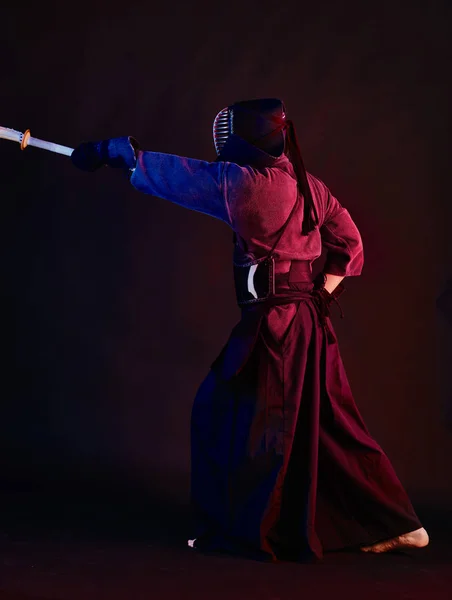 Primer plano, luchador Kendo con armadura, kimono tradicional, casco practicando arte marcial con espada de bambú shinai, fondo negro . —  Fotos de Stock