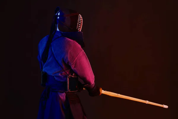 Крупный план, боец Кендо в доспехах, традиционное кимоно, шлем практикующий боевое искусство с бамбуковым мечом Синай, черный фон . — стоковое фото