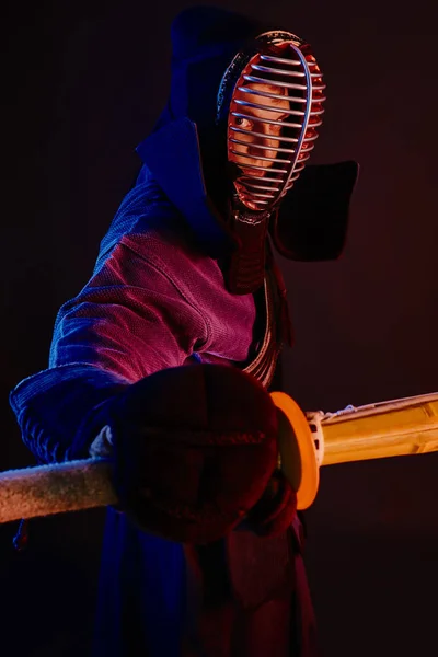 Nahaufnahme, Kendo-Kämpfer in Rüstung, traditioneller Kimono, Helm als Kampfkunst mit Shinai-Bambusschwert, schwarzer Hintergrund. — Stockfoto