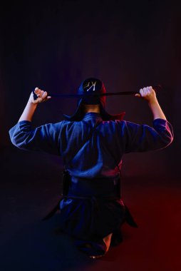 Yakın çekim, Kendo dövüşçüsü zırh giyiyor ve geleneksel kimono kaskının bağcıklarını siyah arka plana doğru bağlıyor..