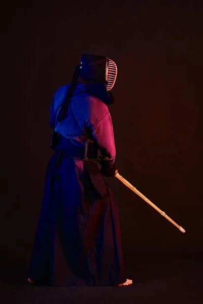 Primer plano, luchador Kendo con armadura, kimono tradicional, casco practicando arte marcial con espada de bambú shinai, fondo negro . —  Fotos de Stock