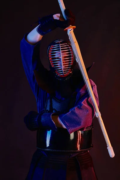 Närbild skott, Kendo fighter bär i en rustning, traditionell kimono, hjälm öva kampsport med shinai bambu svärd, svart bakgrund. — Stockfoto