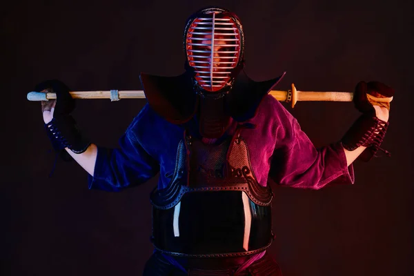Primer plano, luchador Kendo con armadura, kimono tradicional, casco practicando arte marcial con espada de bambú shinai, fondo negro . —  Fotos de Stock