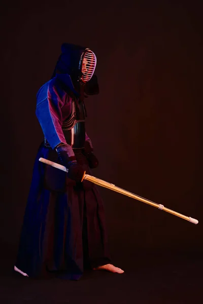 Primer plano, luchador Kendo con armadura, kimono tradicional, casco practicando arte marcial con espada de bambú shinai, fondo negro . —  Fotos de Stock