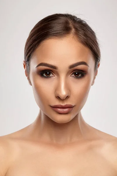 Nahaufnahme Porträt eines brünetten nackten Model-Mädchens mit professionellem Abend Make-up und prallen Lippen, posiert auf grauem Hintergrund. — Stockfoto