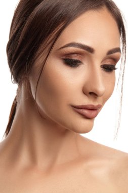 Profesyonel akşam makyajı ve dolgun dudakları olan, beyaz arka planda izole edilmiş esmer, çıplak model bir kızın yakın portresi..