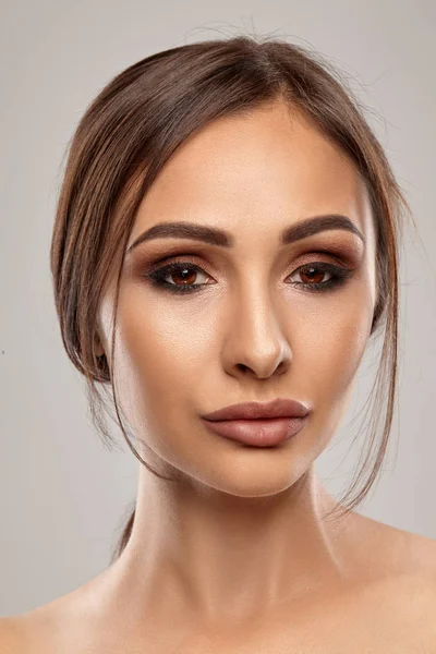 Close-up portret van een brunette naakt model meisje met professionele avond make-up en mollige lippen, poseren op grijze achtergrond. — Stockfoto