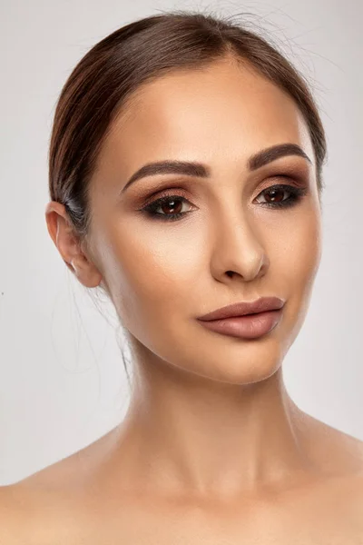 Close-up portret van een brunette naakt model meisje met professionele avond make-up en mollige lippen, poseren op grijze achtergrond. — Stockfoto