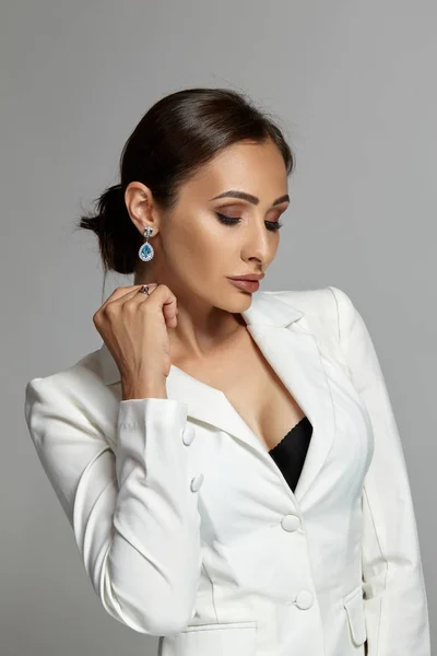 Close up portrait of a brunette model girl with professional evening make-up, wearing a white jacket with black bra, posing on gray background. — Stock Photo, Image