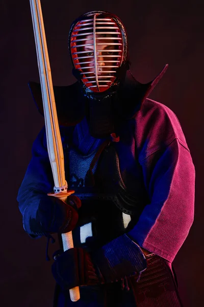 Close-up schot, Kendo vechter dragen in een harnas, traditionele kimono, helm beoefenen van krijgskunst met shinai bamboe zwaard, zwarte achtergrond. — Stockfoto