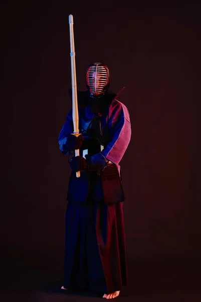 Primer plano, luchador Kendo con armadura, kimono tradicional, casco practicando arte marcial con espada de bambú shinai, fondo negro . —  Fotos de Stock