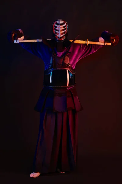 Közelkép, Kendo harcos visel páncélt, hagyományos kimonó, sisak gyakorló harcművészet Shinai bambusz kard, fekete háttér. — Stock Fotó