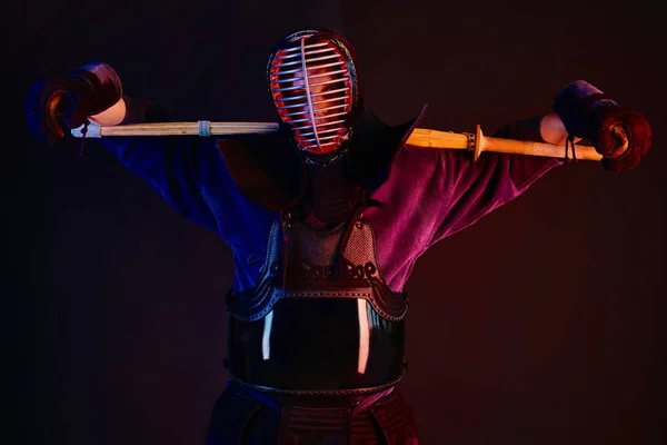 Зблизька стрілянина, боєць Кендо, одягнений в обладунки, традиційний кімоно, шолом практикує бойове мистецтво з шинайським бамбуковим мечем, чорний фон. — стокове фото