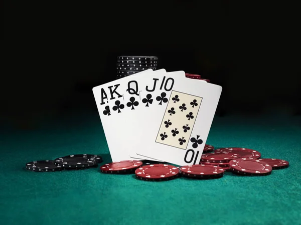 Winning combination in poker standing leaning on colored chips piles on green cover of playing table. Black background. Close-up. — Stock Photo, Image
