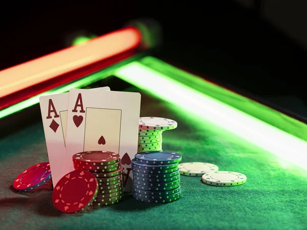 Dos ases apoyados en pilas de papas fritas, algunas de ellas colocadas en la cubierta verde de la mesa de juego, bajo luces de neón verdes y rojas. Primer plano . — Foto de Stock