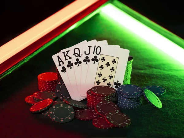 Combinação vencedora no poker em pé apoiando-se em pilhas de chips multicoloridos na tampa verde da mesa de jogo, sob luzes verdes e vermelhas, néon,. Close-up . — Fotografia de Stock