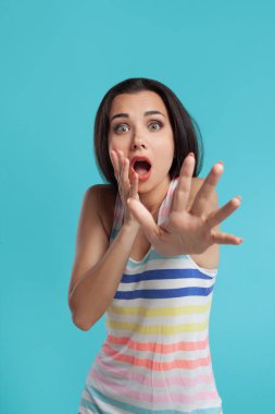 Uzun saçlı, renkli çizgili gömlekli, mavi stüdyo arka planında poz veren esmer bir kadın. Samimi duygular. Yakın plan..