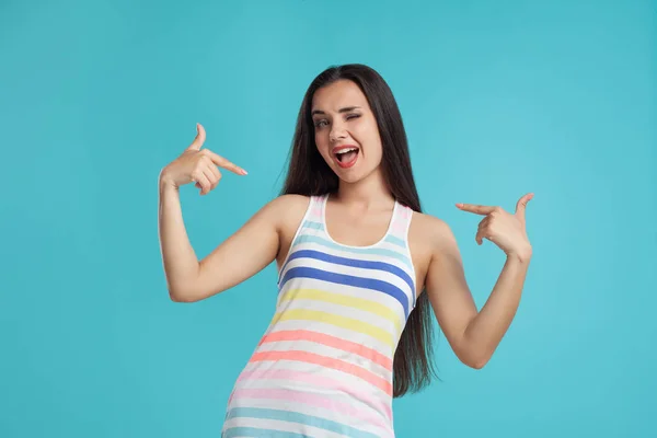 Mulher morena com cabelos longos, vestida com camisa listrada colorida, posando contra fundo estúdio azul. Emoções sinceras. Close-up. — Fotografia de Stock