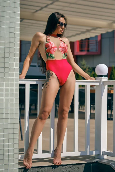 Портрет женщины, отдыхающей в рекреационном центре или гостинице с бассейном. Одетые в красочный купальник и солнцезащитные очки . — стоковое фото