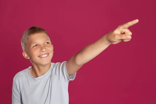 티셔츠를 금발의 아이의 분홍색 스튜디오 배경에 포즈를 취하면서 미소를 지으며 — 스톡 사진