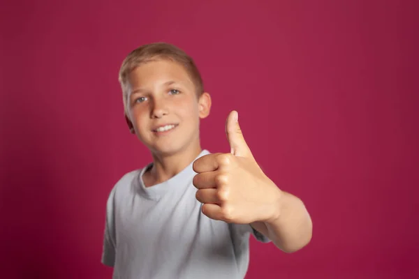 티셔츠를 스러운 소년의 클로즈업 분홍색 스튜디오 배경을 배경으로 포즈를 취하면서 — 스톡 사진