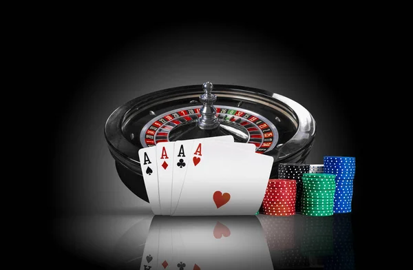Four aces standing on a mirror surface with backlight, ahead of dark roulette and chips in piles. Black background. Gambling entertainment. Close-up. — Stock Photo, Image