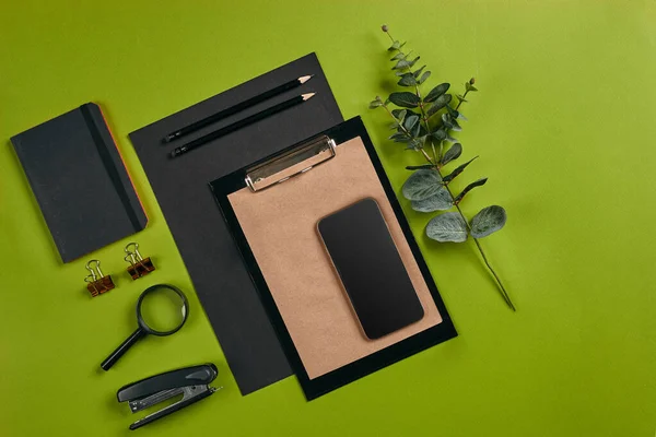 Top view in focus with different office equipment, supplies, stationery. Green background with copy space. Education, workplace concept. Close-up. — Stock Photo, Image