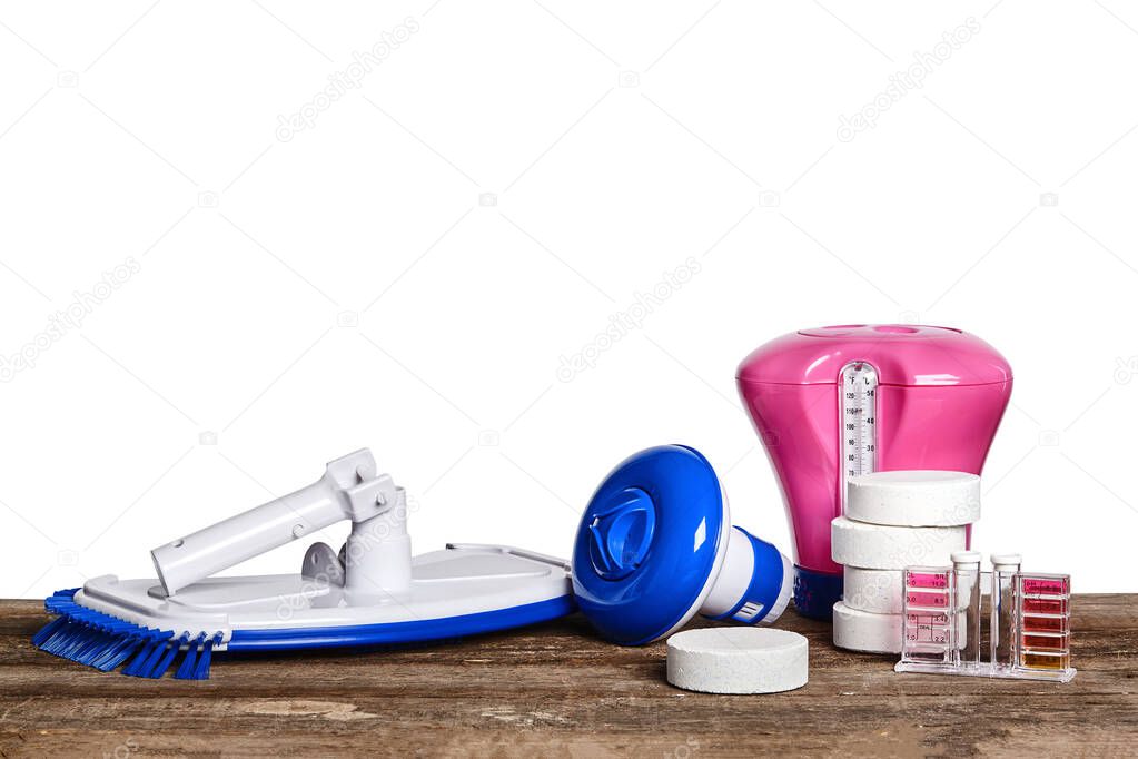 Equipment with chemical cleaning products and tools for the maintenance of the swimming pool on a wooden surface against white background.