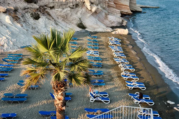 Widok na morze z palmą, leżaki na czystym piasku. Biały kamienny przylądek na wyspie Kalymnos lub Gubernator Beach na Cyprze. Plaża Morza Śródziemnego. — Zdjęcie stockowe